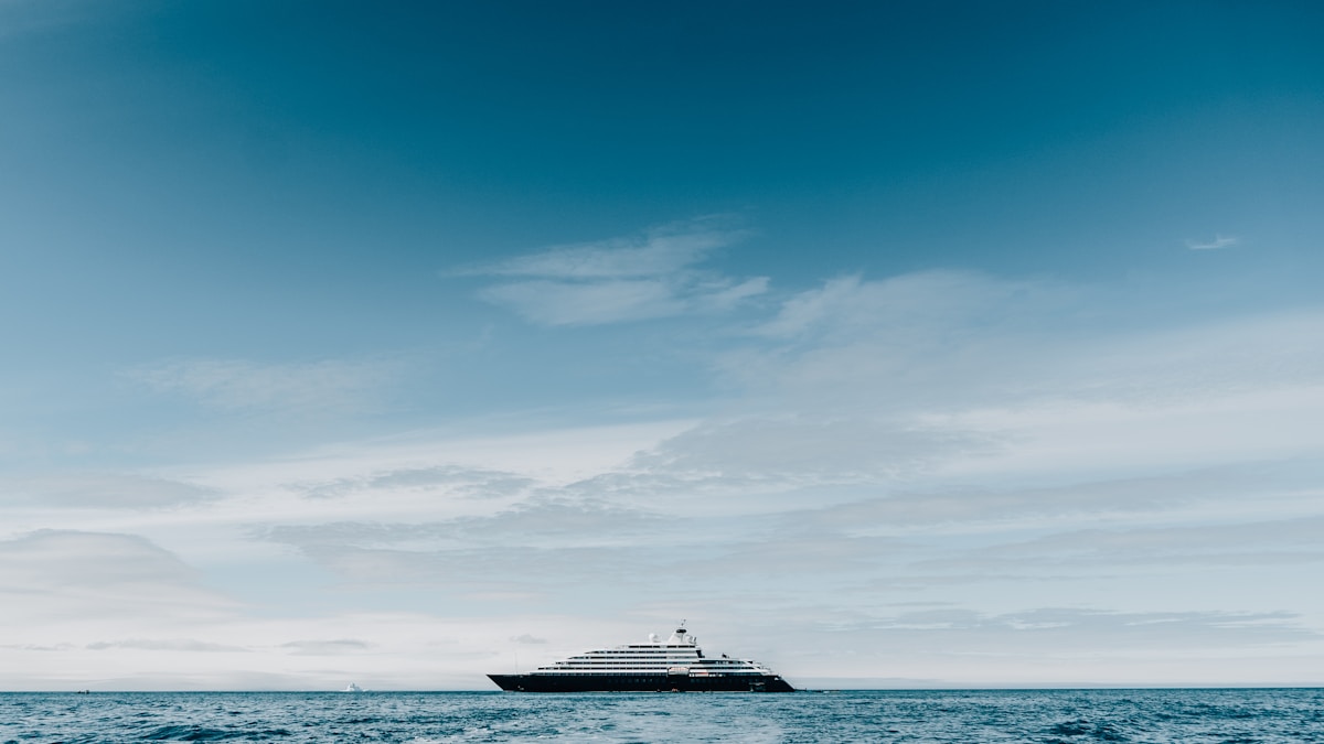 An expedition cruise ship crossing the Antarctic sea under a clear blue sky