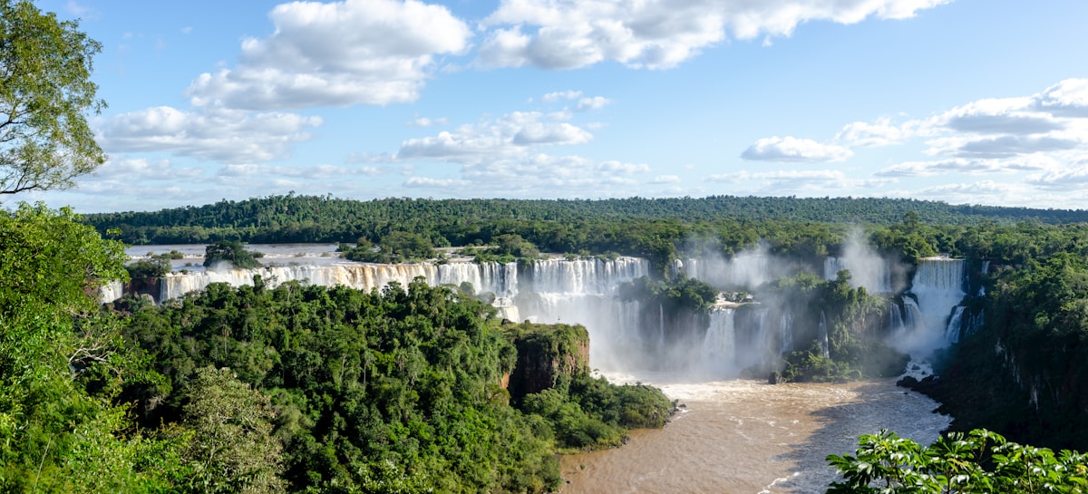 Panoramic view of Iguazu Falls waterfalls surrounded by dense jungle under a cloudy sky