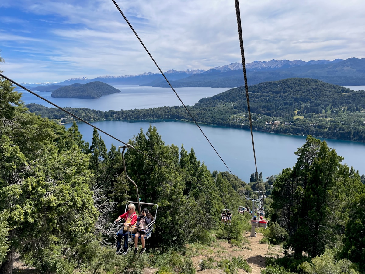 People on a ski lift above Nahuel Huapi Lake and mountains, Bariloche, Argentina