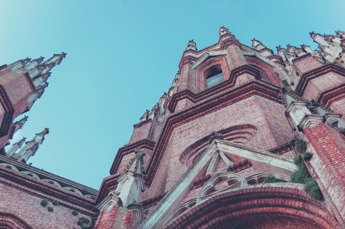 Neo-Gothic facade of La Plata Cathedral with flying buttresses and tall spires against blue sky, La Plata, Buenos Aires Province, Argentina