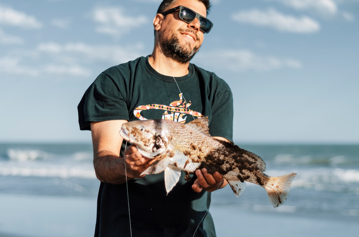Fisherman holding a freshly caught fish on an Atlantic coast beach in Argentina