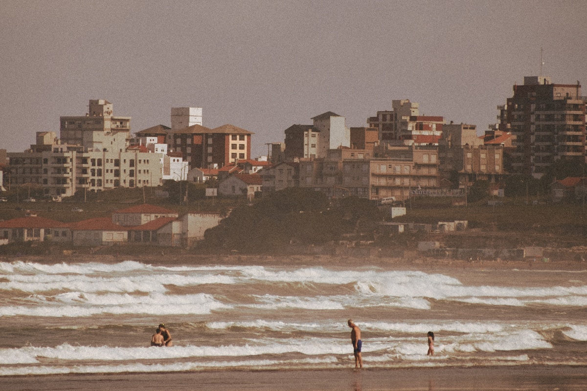 Surfers in the water at Mar del Plata beach with the city skyline behind, Argentina