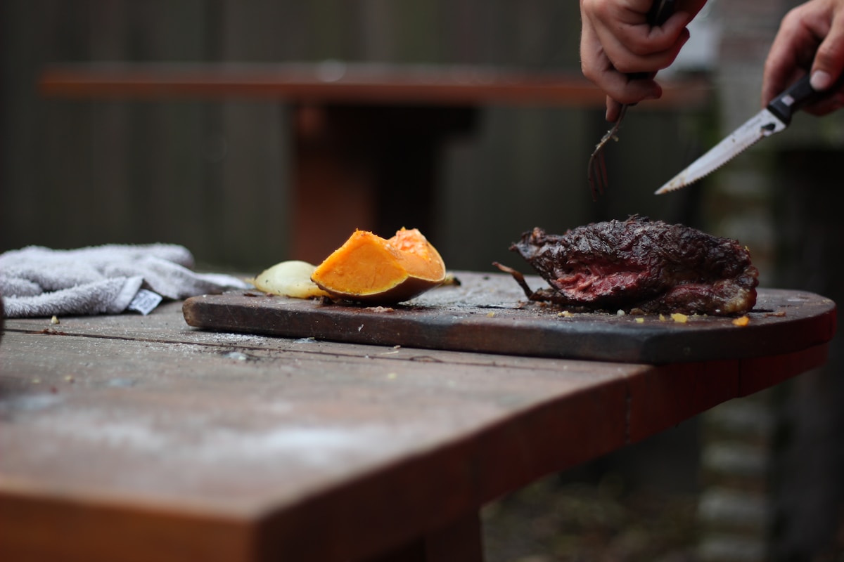 Outdoor asado carving - grilled beef and pumpkin on a wooden board in a Patagonian setting
