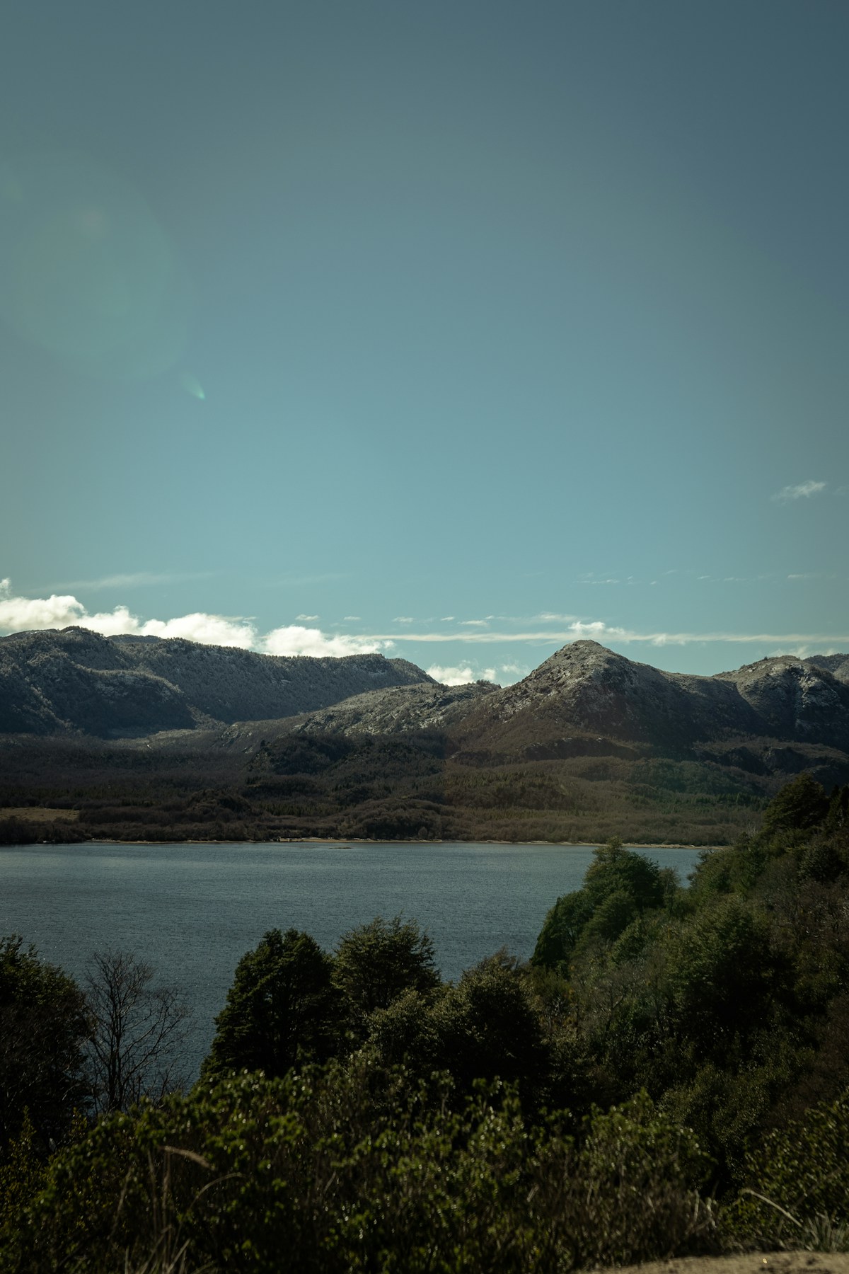 Lago Lácar surrounded by forested Andes mountains under a blue sky, San Martín de los Andes, Argentina