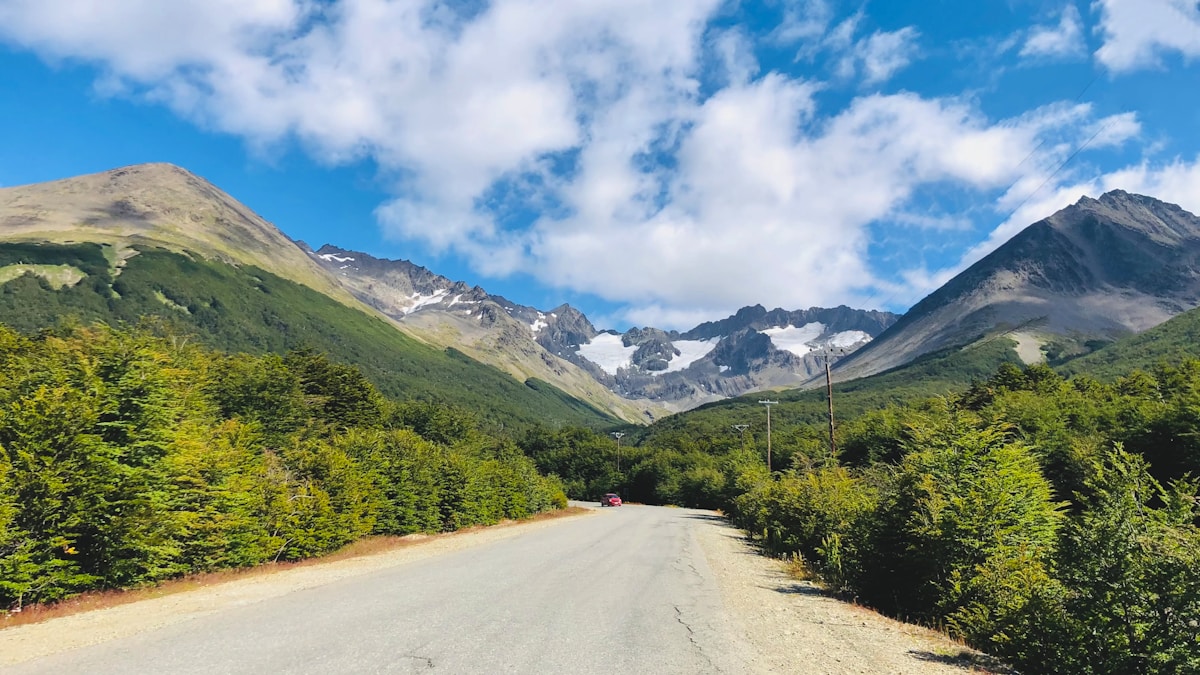 Mountain road through green forest leading to snow-capped peaks, Ushuaia, Tierra del Fuego, Argentina