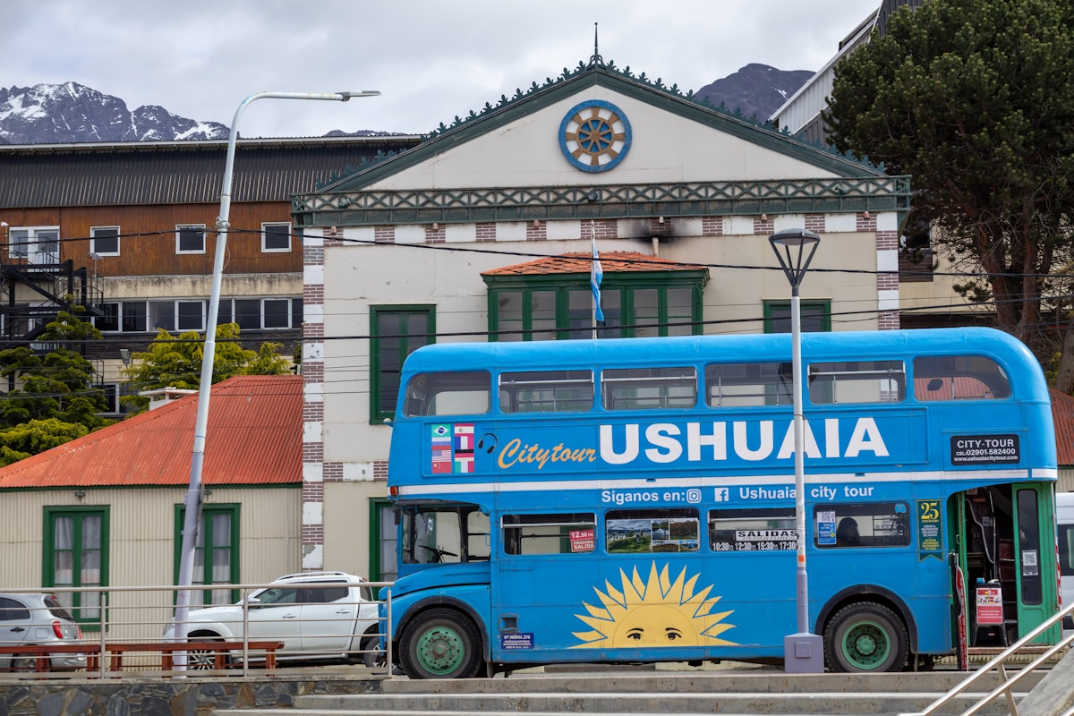 City tour bus in Ushuaia with snow-capped Andes mountains in the background