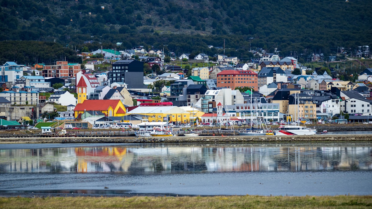 Colourful waterfront buildings of Ushuaia reflected in the calm waters of the Beagle Channel, Tierra del Fuego, Argentina